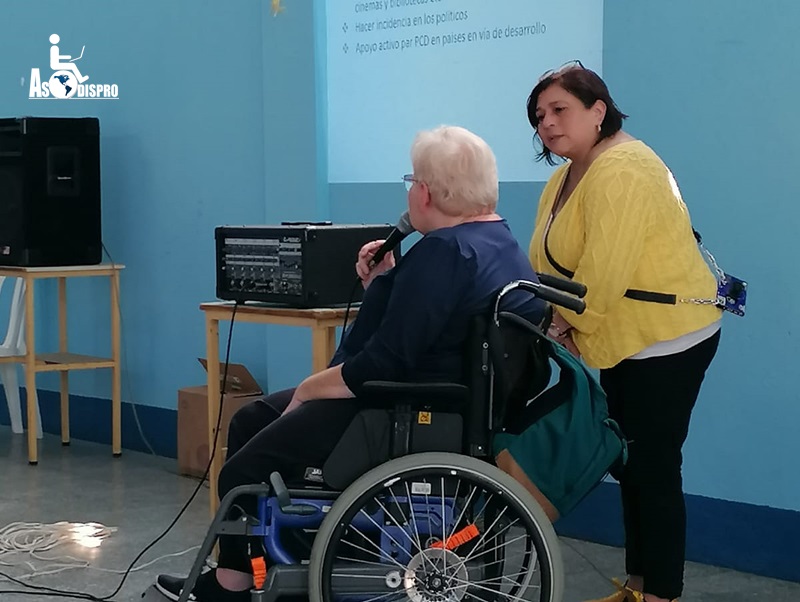 En su silla de ruedas, con micrófono en mano, y apoyada por una interprete, Ulla diserta a los asistentes al evento.