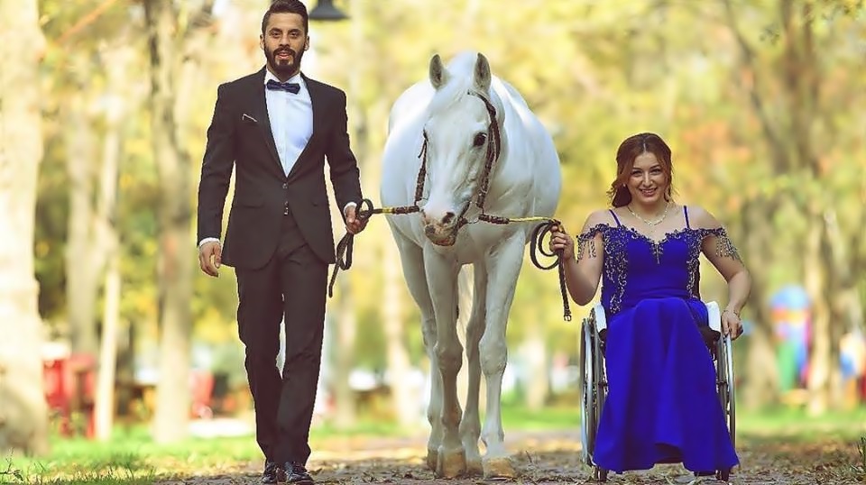 En unas tarde soleada, en una vereda, una pareja de novios llevan a un caballo de sus riendas, él va de un lado vestido de etiqueta y ella va del otro lado en silla de ruedas y con un vestido de noche azul.