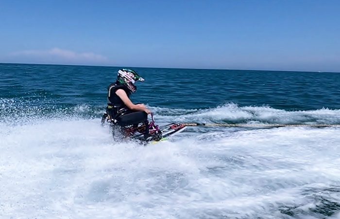 Una persona con casco y silla de ruedas, es halado en pleno mar al practicar esquí acuático 