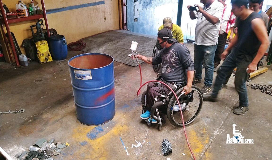 Durante una capacitación de Asodispro sobre mecánica, una persona con discapacidad física usuaria de silla de ruedas, punta con un soplete un tonel. 