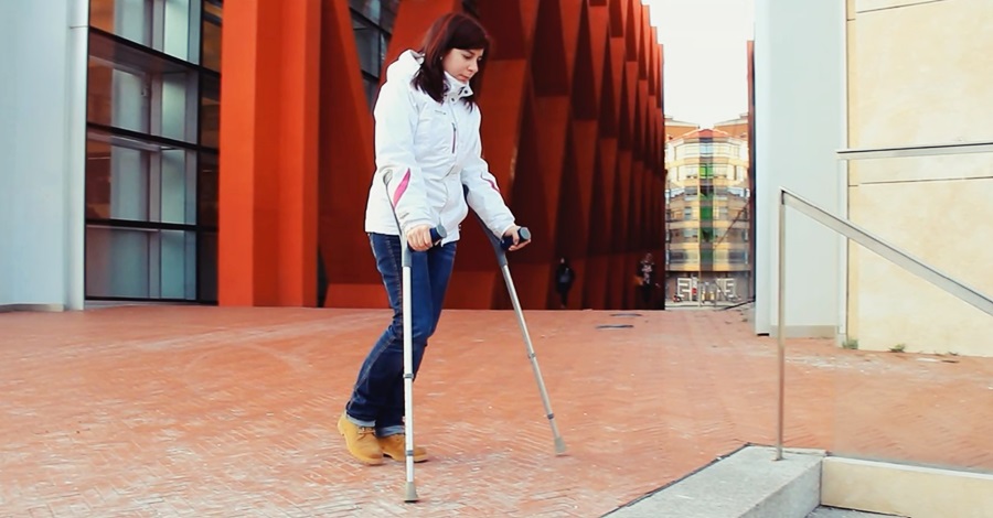 Una chica camina por la calle con muletas 