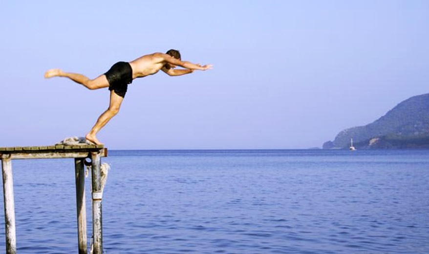 Un hombre efectúa un clavado en un lago. 