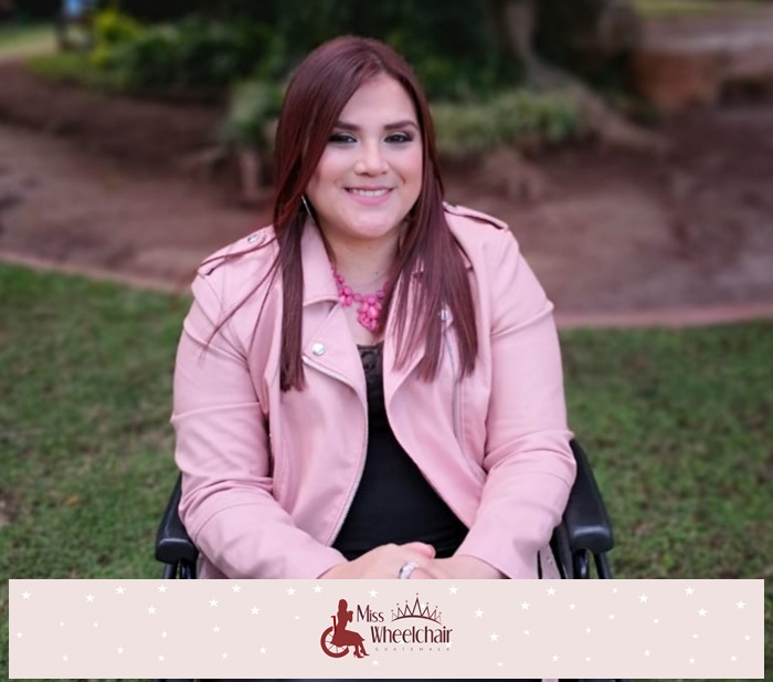 Fotografía de medio cuerpo, Ana Lucrecia Fernández en su silla de ruedas sonríe a cámara, maquillada en tono rosa, vistiendo traje negro y chaqueta rosada. 