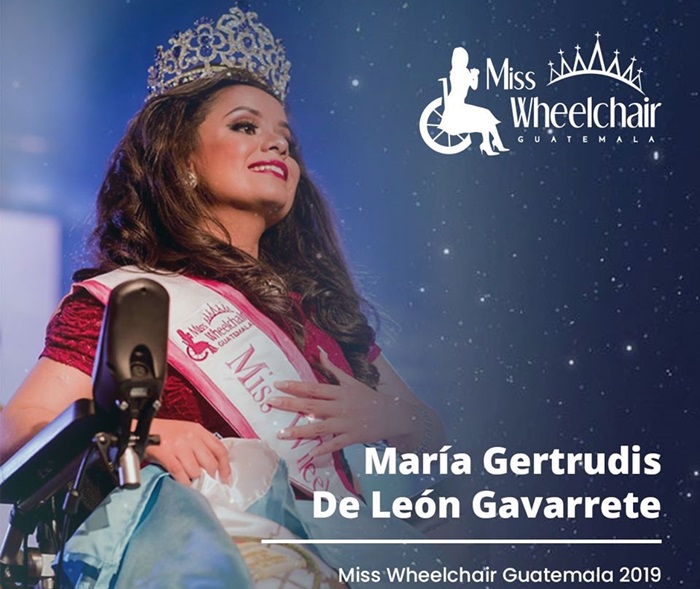 En su vestido de noche, la reina electa sonríe con los ojos llorosos, y pone una de sus manos sobre su pecho, como sosteniendo la banda que la acredita como Miss Wheelchair Guatemala, en su cabeza de igual forma porta una corona color oro con incrustaciones blancas y azules. 