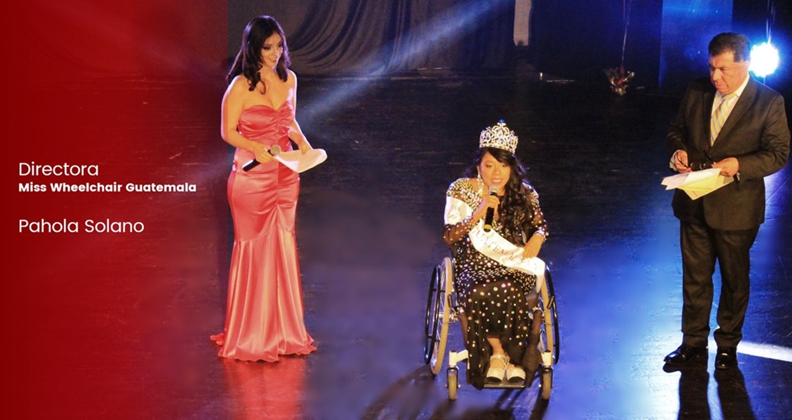 En un escenario, en su silla de ruedas, con su corona y vestido negro con lentejuelas, Pahola Solano se dirige al público con un micrófono. 