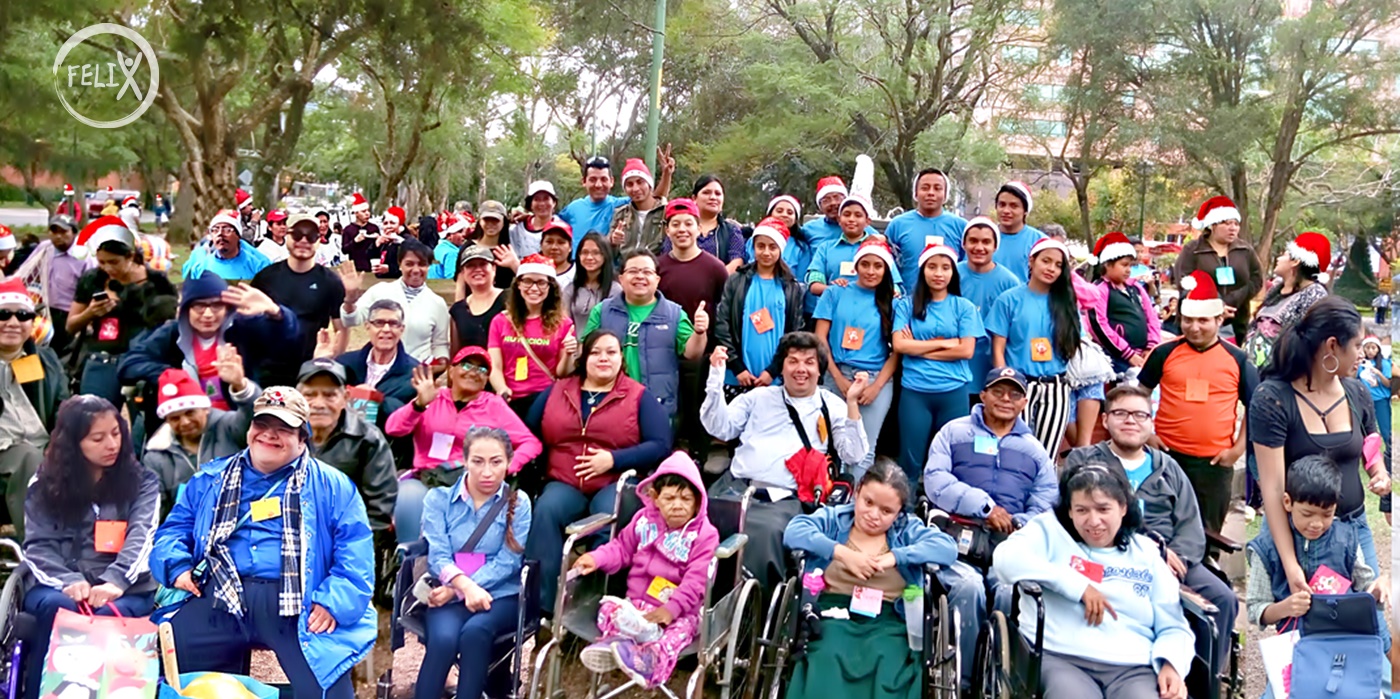 Yojana Chávez de Asodispro está en su silla de ruedas, abraza a un chico con síndrome Down mientras le entrega un presente navideño de la ONG Felix, área benéfica para personas con discapacidad de Asodispro Guatemala