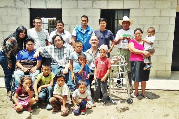 Frente a una casa nueva de blocks, Byron Pernilla está con la familia beneficiada con ayudas, así como junto a voluntarios.