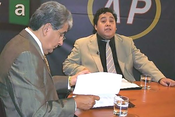 Byron P	ernilla se dirige a cámara mientras el doctor Francisco Arredondo revisa unos documentos durante una entrevista de televisión.