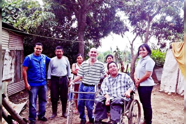 En un patio de tierra, junto a una casa de lámina, Byron Pernilla posa en su silla de ruedas junto a voluntarios de la segunda carrera benéfica.