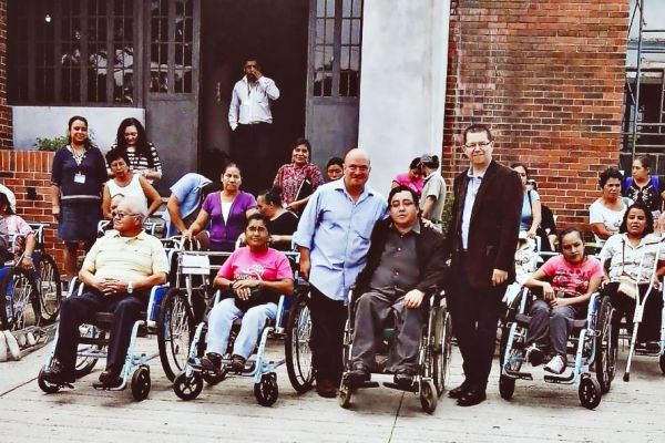 Dos funcionarios del Ministerio de Desarrollo Social, están junto a Byron Pernilla, tras ellos se ven varias personas en silla de ruedas, esto, tras la finalización de una entrega de donación de implementos para personas con discapacidad.