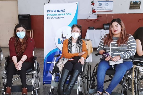 Frente a un baner de Asodispro, las tres chicas posan para la fotografía en su silla de ruedas