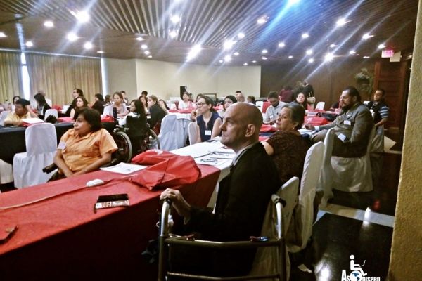 Bajo las luces de un gran salón, se observan personas con discapacidad en sus mesas